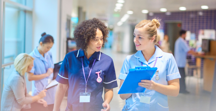 Two NHS nurses walking through a hospital corridor