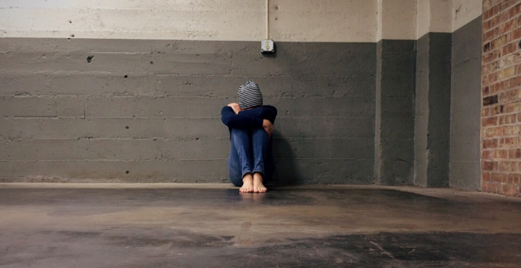 person sitting on the floor, head resting on knees