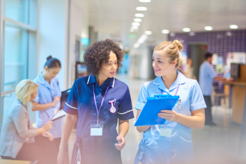 Two NHS nurses walking through a hospital corridor