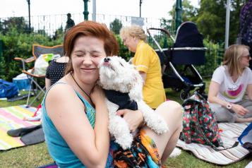 Woman smiling and holding her dog in the park