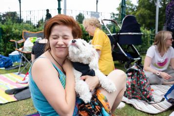 Woman smiling and holding her dog in the park 